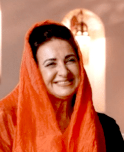 A radiant smiling woman in an orange head scarf