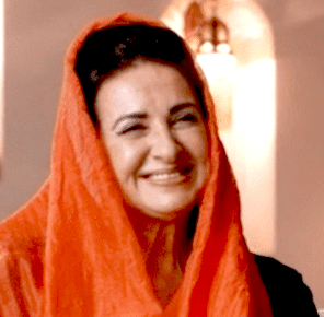 A radiant smiling woman in an orange head scarf